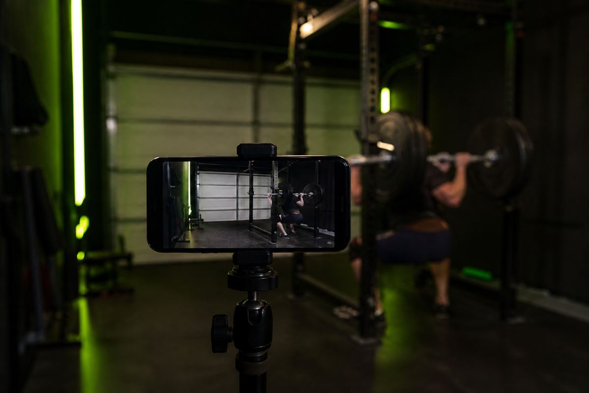 Phone on a tripod filming a squat rack